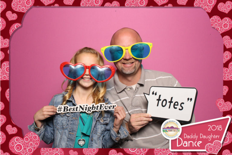 Man and young girl with glasses and props posing with pink backdrop