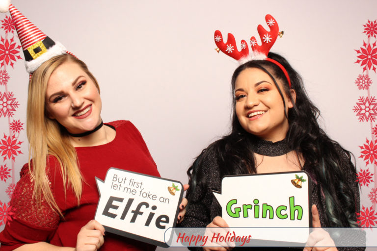 Two women posing with Christmas props and white backdrop
