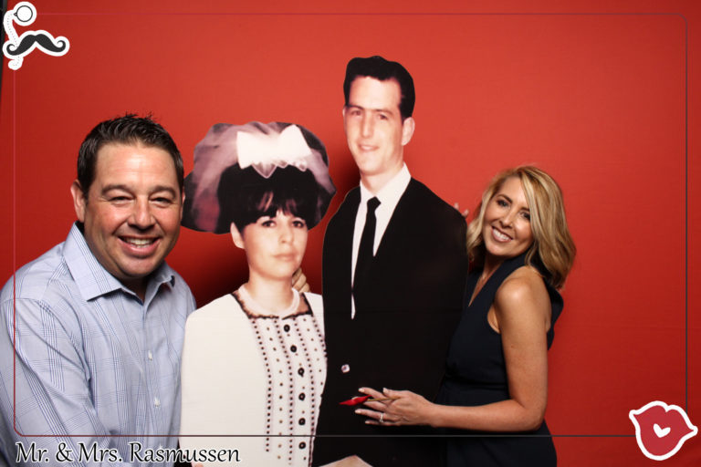 Couple with cardboard cut outs posing with red backdrop