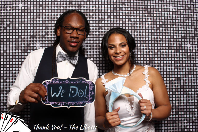 Couple with props posing in front of silver shimmer backdrop