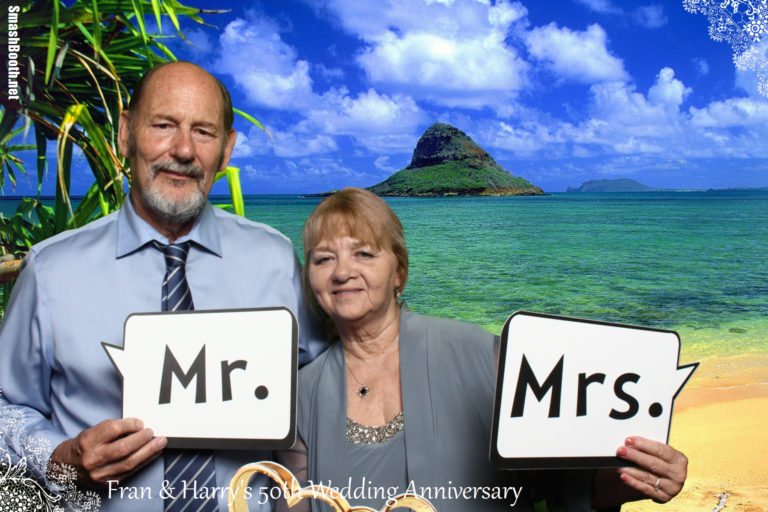 Couple with sign props posing in front of outdoor beach background