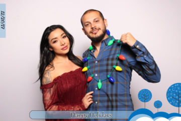 Couple posing with holiday light prop and white backdrop