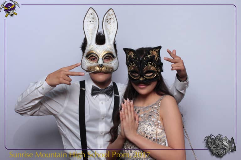 couple posing in front of white backdrop with mask props