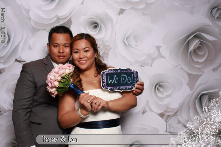 Couple posing with props and flower wall white backdrop
