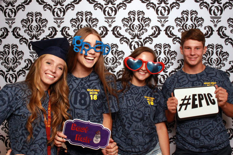 Group with glasses and props posing with damask backdrop