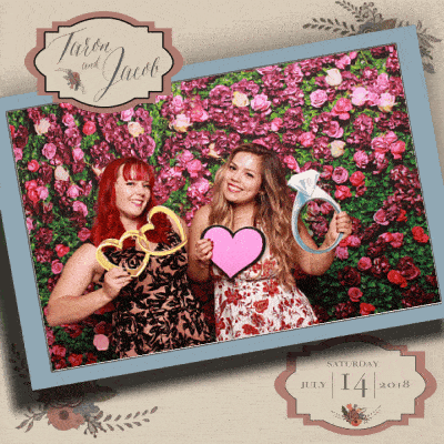 Two women posing with props and rose wall backdrop