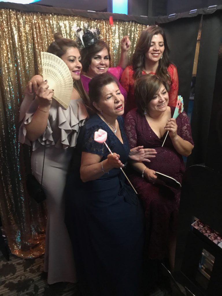 Group of women in an enclosure posing with a gold backdrop and props