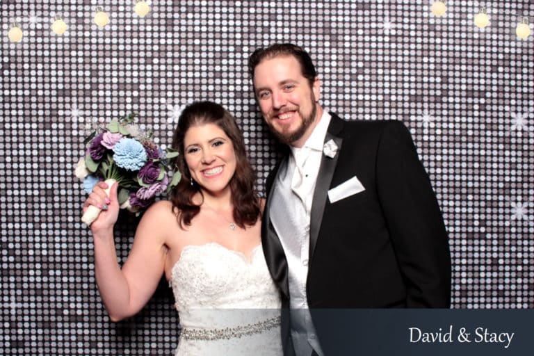 Couple posing with props in front of silver shimmer backdrop