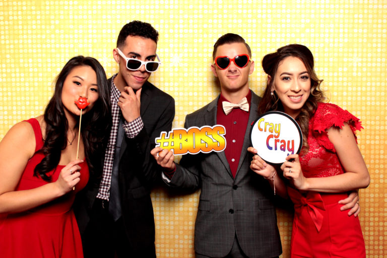 Group with props and sunglasses posing in front of gold backdrop