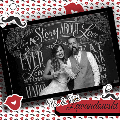 Black and white image of couple posing with chalkboard backdrop