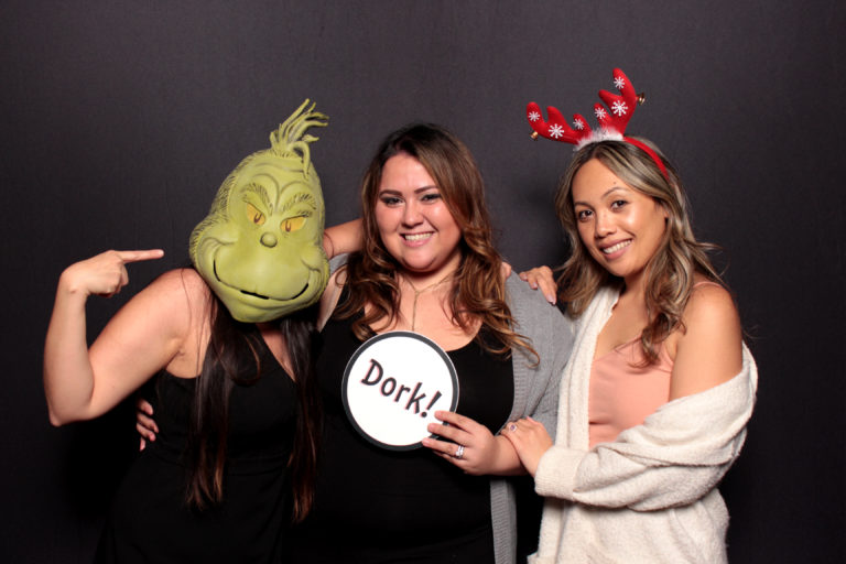 Group with Christmas props posing in front of black backdrop grinch mask