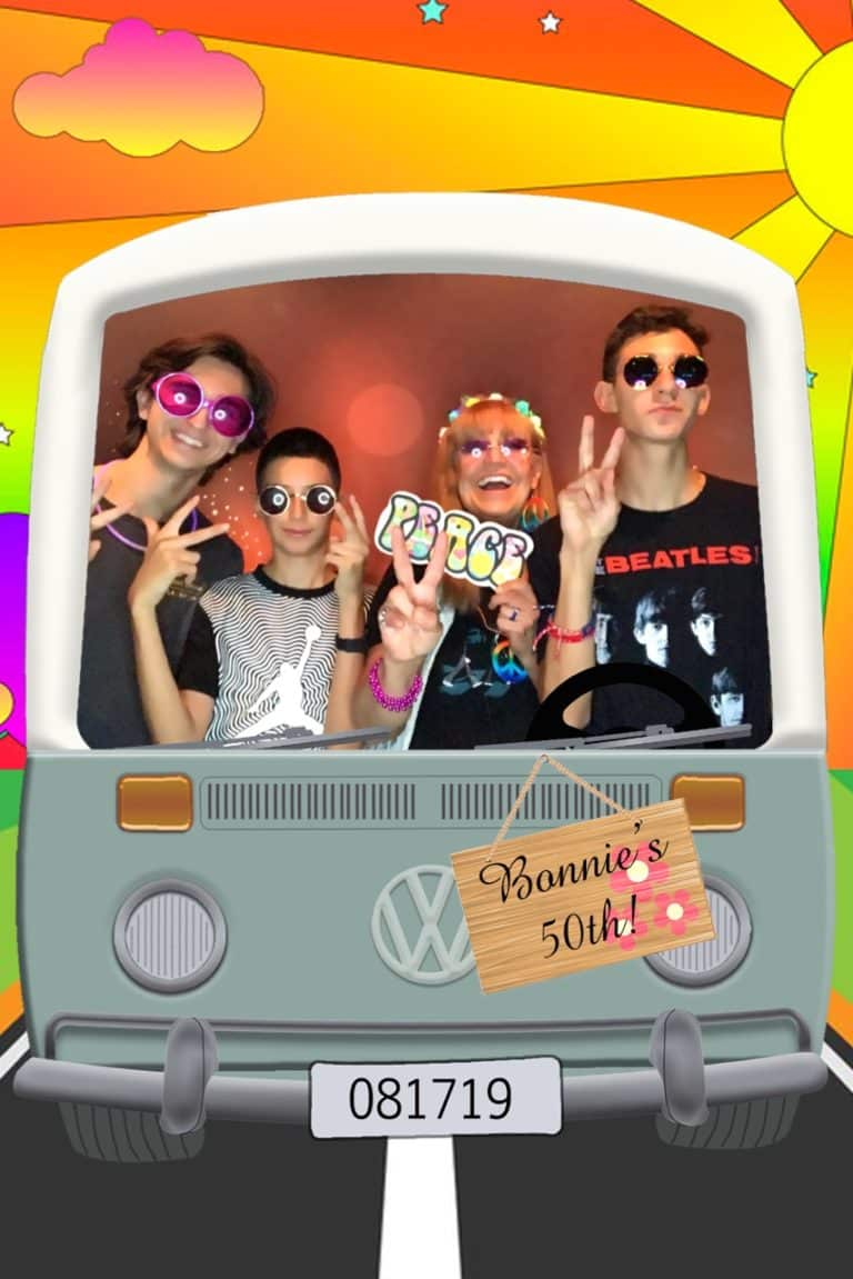 Group in hippie costumes in front of colorful backdrop in van photo strip
