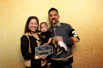 Couple with baby posing in front of gold shimmer backdrop with props