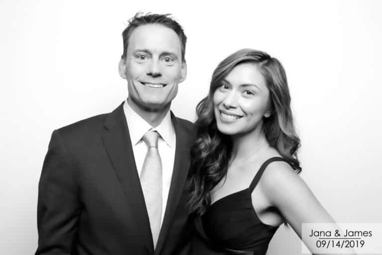 Black and white image of couple posing with white backdrop