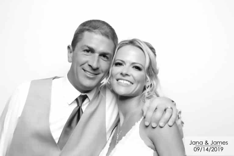 Black and white image of a couple posing with a white backdrop