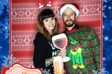 couple posing with ugly sweater backdrop and props