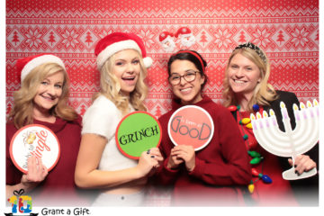 group of women posing with ugly sweater backdrop and Christmas props