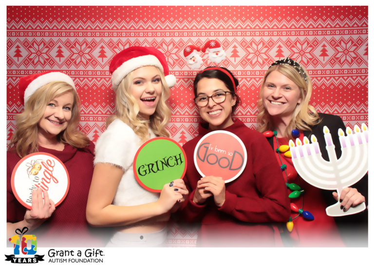 group of women posing with ugly sweater backdrop and Christmas props