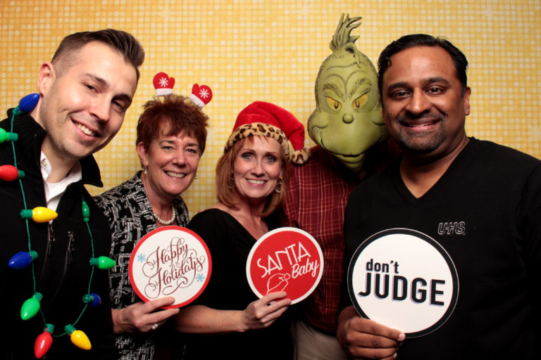 group posing with gold backdrop and Christmas props with grinch costume