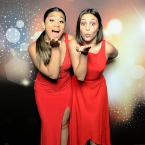 two women in red dresses pose with dark bokeh backdrop Photo Booth Rentals in Las Vegas Smash Booth
