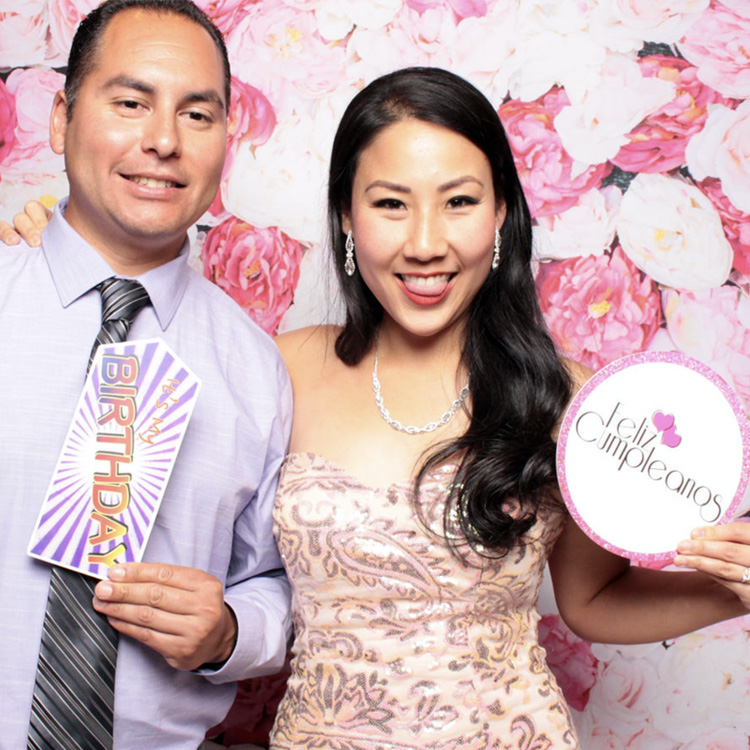 couple posing with flower wall backdrop
