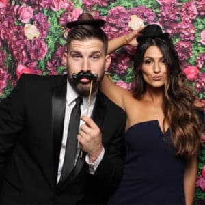 couple posing with flower backdrop and props Photo Booth Rentals in Las Vegas Smash Booth