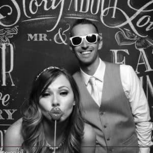 black and white image of couple posing with chalkboard backdrop and props