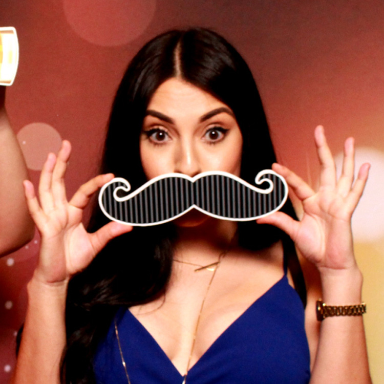 woman posing with mustache prop and backdrop