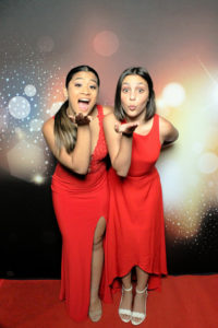 two women in red dresses posing with dark bokeh backdrop Photo Booth Rentals in Las Vegas Smash Booth
