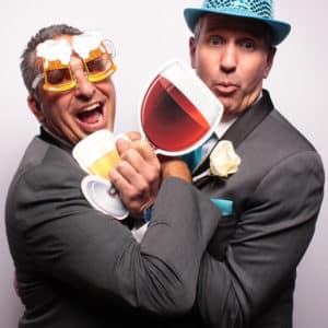 two men posing with white backdrop and props giant wine glass