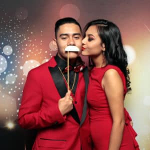 couple in red posing in front of dark bokeh backdrop with props Photo Booth Rentals in Las Vegas Smash Booth