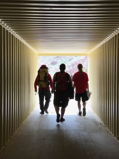 three people walking down hallway facing away