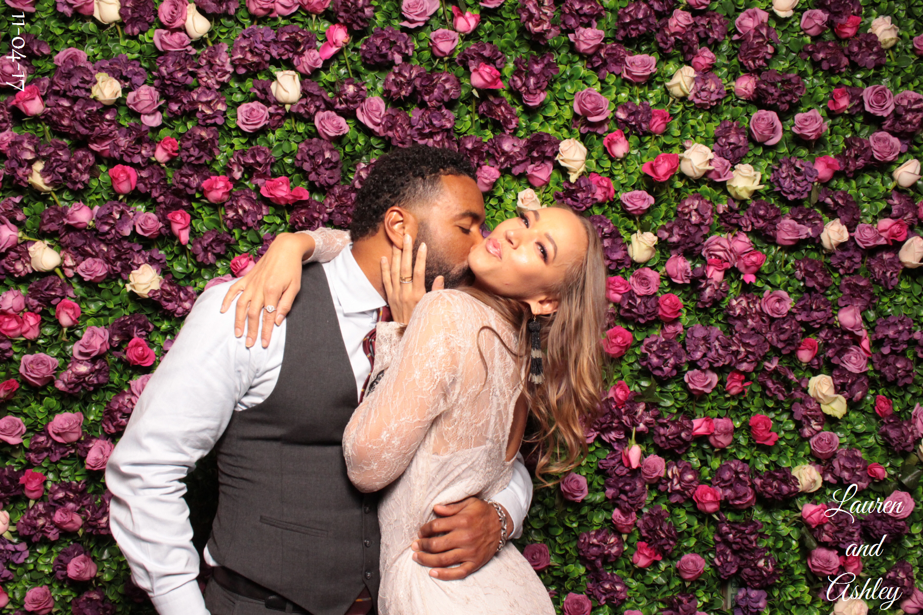 couple posing in front of a flower backdrop in the photo booth