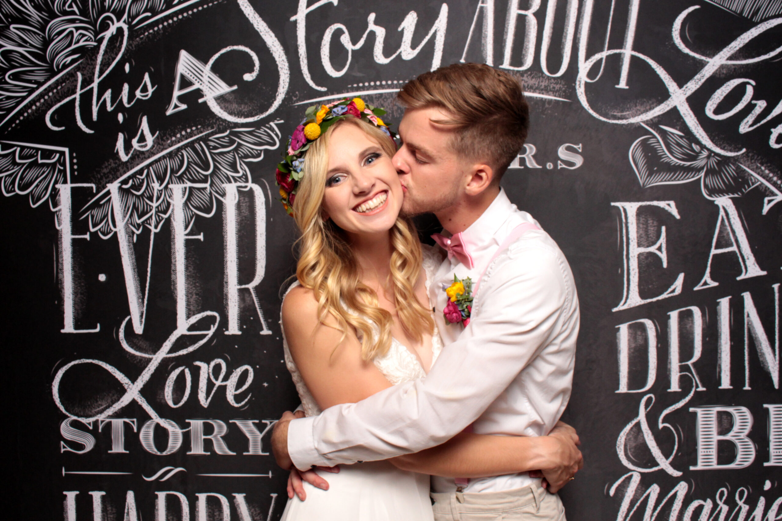wedding couple posing in front of a chalkboardbackdrop in the photo booth