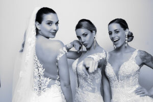 three-women-in-wedding-dresses-pointing-toward-camera-in-photo-booth