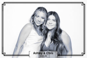 two-women-smiling-in-photo-booth-with-event-label