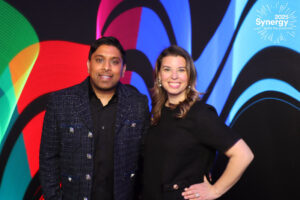two-people-posing-in-front-of-colorful-abstract-backdrop-at-smash-booth-event