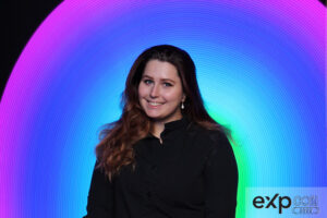 woman-smiling-in-front-of-a-blue-light-swirl-backdrop-at-smash-booth
