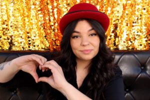 woman-in-red-hat-making-heart-hand-sign