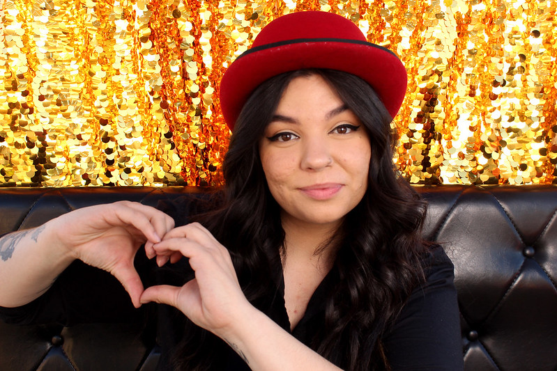 woman-in-red-hat-making-heart-hand-sign