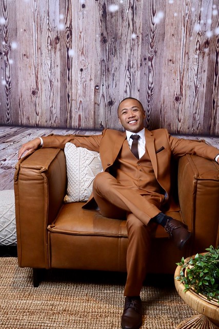 man-in-brown-suit-posing-in-leather-chair-at-smash-booth-event