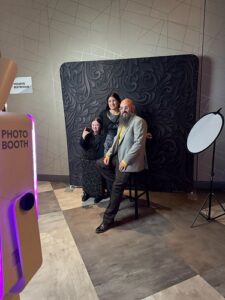 two-men-posing-in-front-of-black-floral-backdrop-at-smash-booth-photo-booth