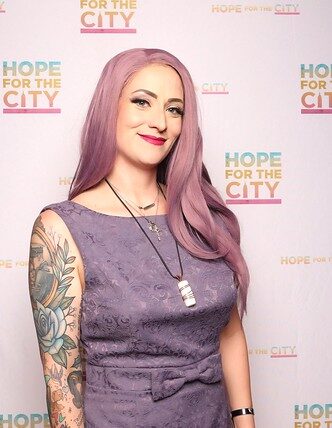 woman-with-purple-hair-smiling-in-front-of-hope-city-event-banner-at-smash-booth