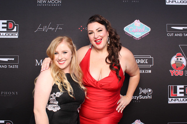 two-women-in-red-dress-and-black-gown-posing-at-smash-booth-event