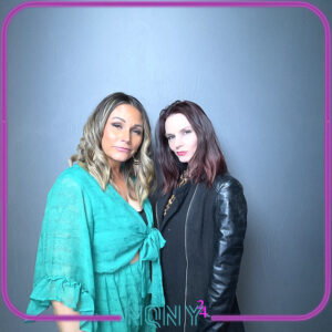 Two-women-posing-at-photo-booth-with-neon-style-lighting-and-teal-outfits