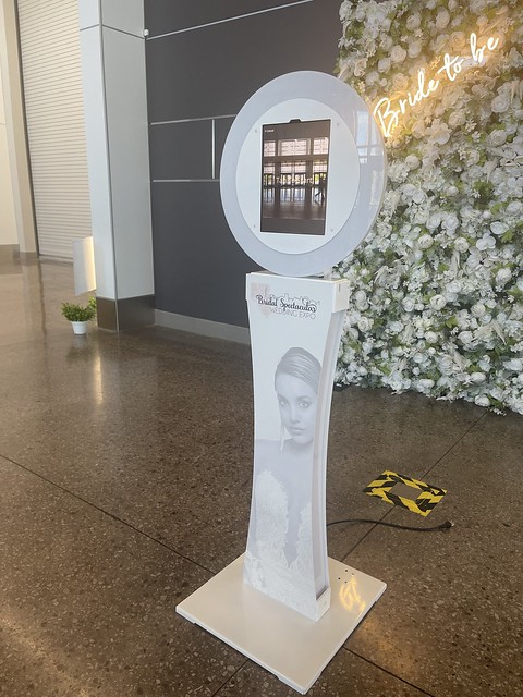 Sleek-white-photo-booth-stand-set-up-on-tiled-flooring-for-outdoor-event