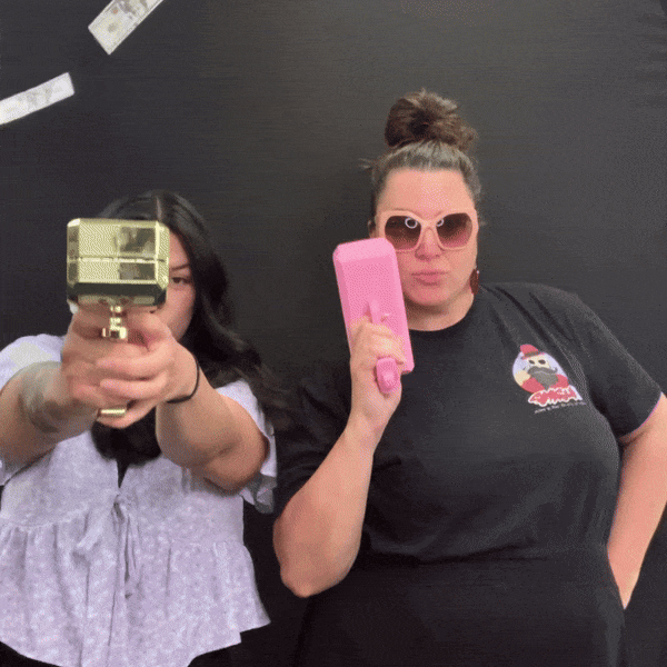 Two-guests-holding-up-custom-photo-booth-prints-with-black backdrop